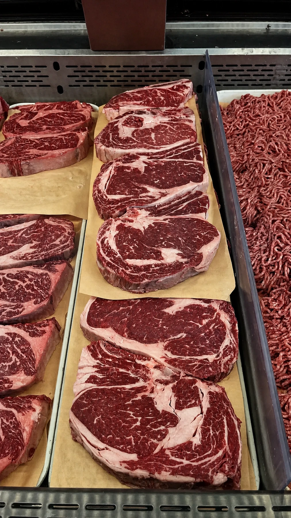 Fresh marbled ribeye steaks in the butcher case