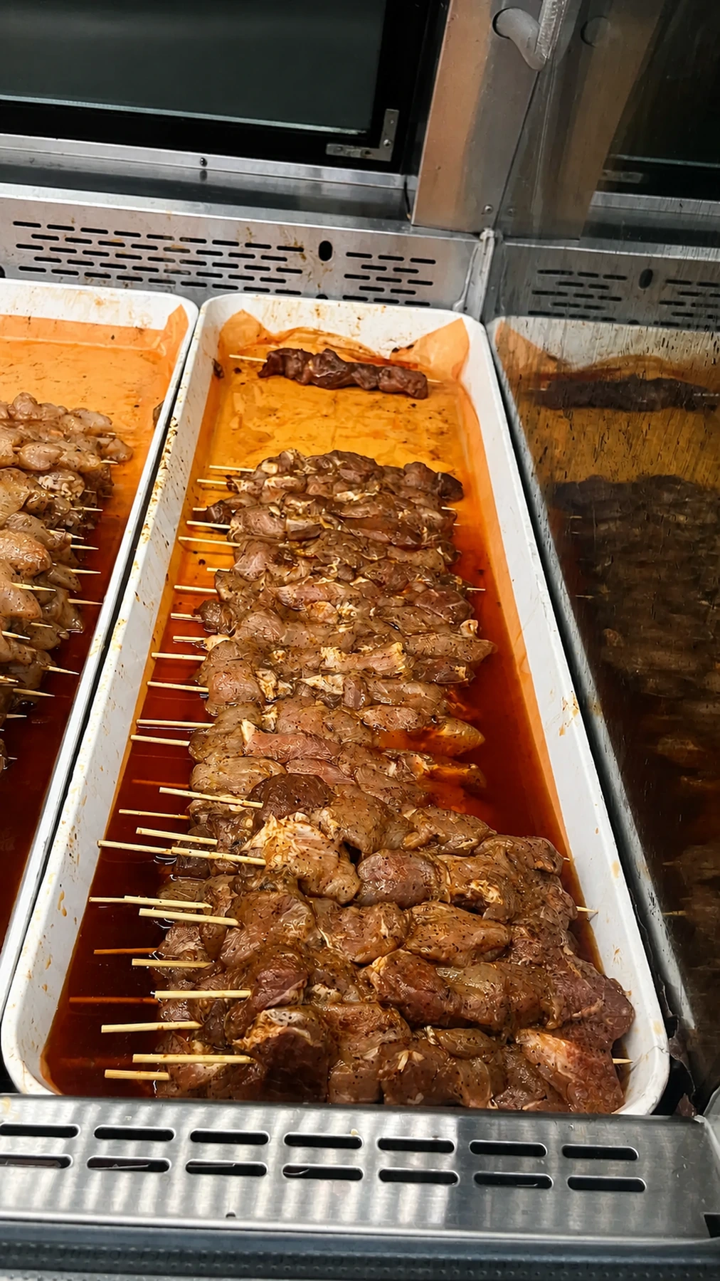 Seasoned meat souvlaki skewers in the display case